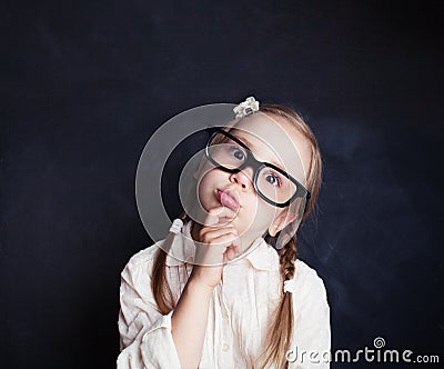 Ð¡urious child thinking. Funny little girl in glasses Stock Photo